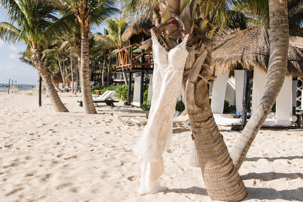 wedding dress hanging from a palm tree, blowing in the wind on the beach